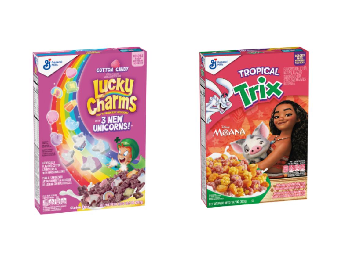 ​Two General Mills cereal boxes are shown against a white background. On the left is a pink box of "Cotton Candy Lucky Charms," featuring Lucky the Leprechaun, a rainbow, and an announcement of "3 NEW UNICORNS!". On the right is a red box of "Tropical Trix," featuring the Trix Rabbit, Disney's Moana, and her pig Pua next to a bowl of the colorful cereal.