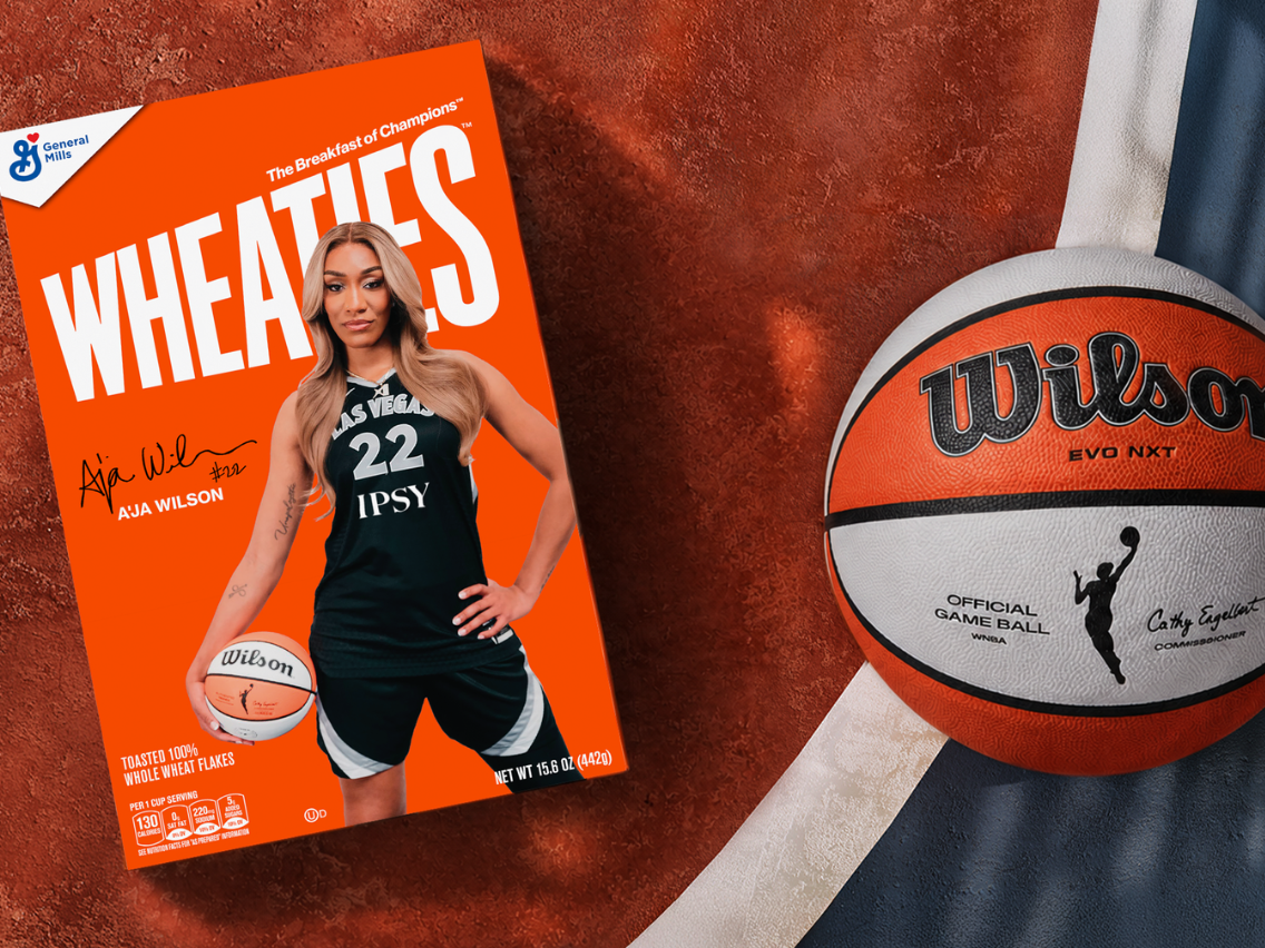 Visual of the new A’ja Wilson Wheaties box next to a Wilson basketball on an outdoor basketball court.